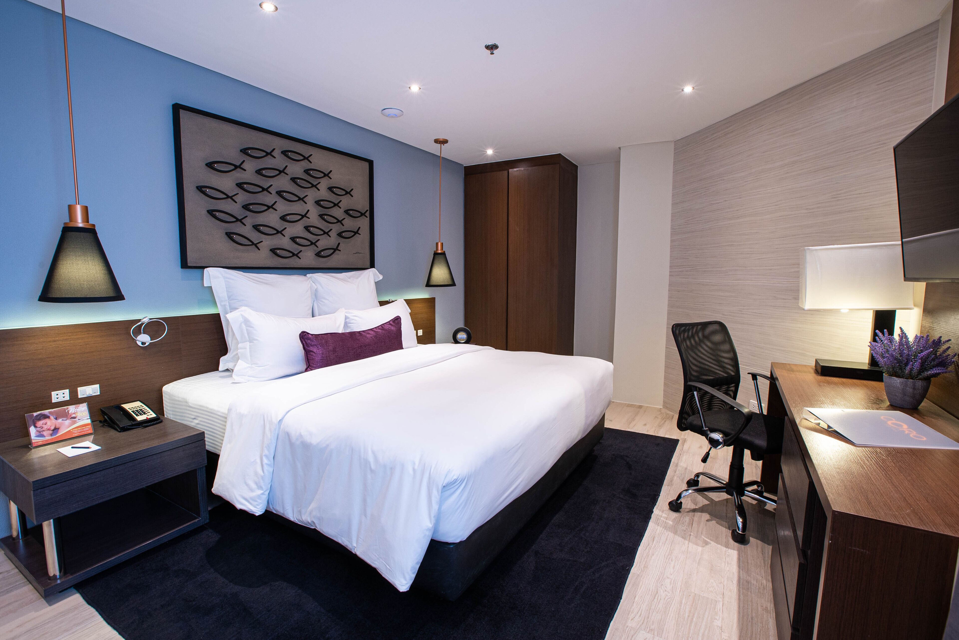 A modern hotel room with a large bed, bedside tables, a desk, and a chair.