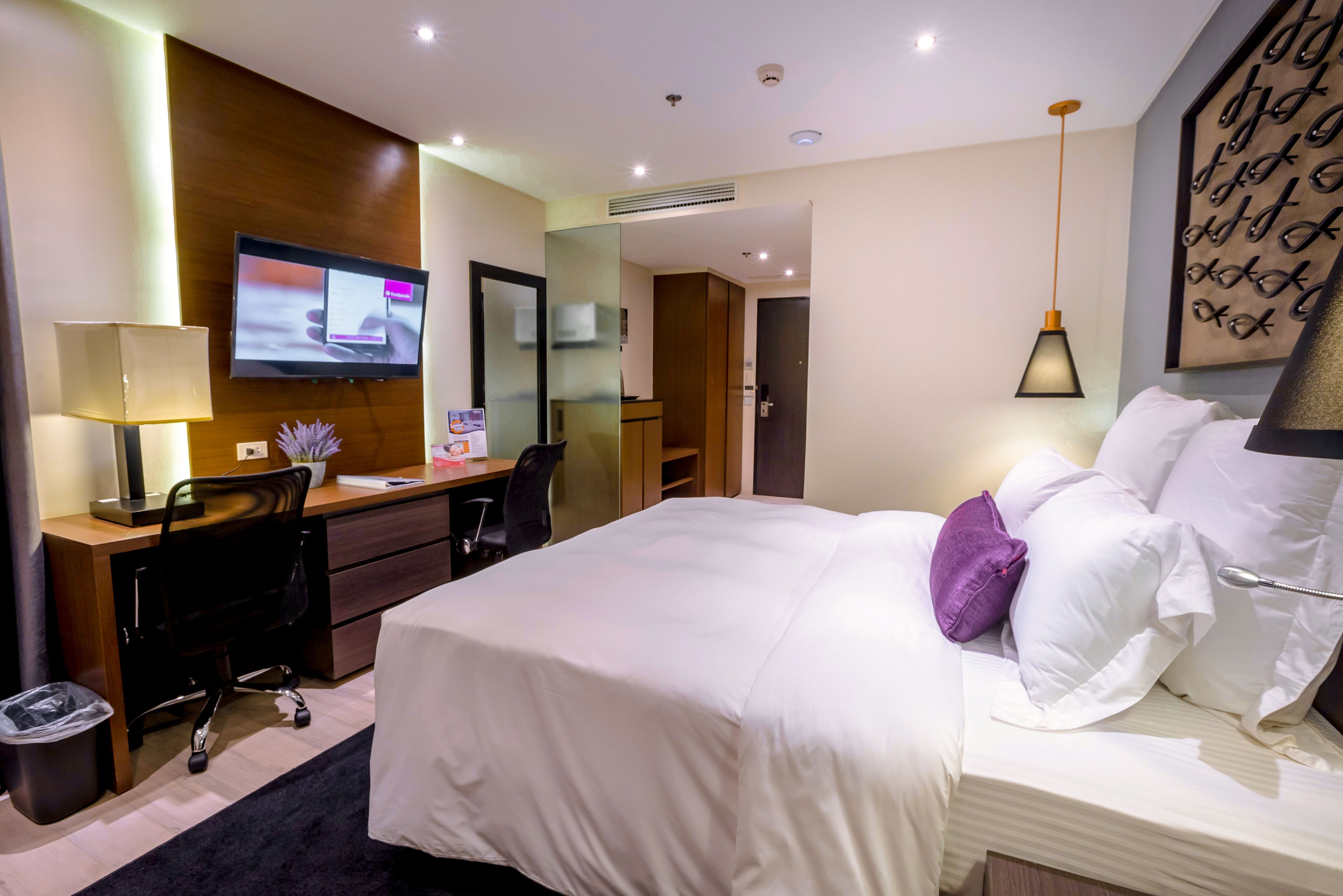 A hotel room with a bed, desk, chair, TV, and a mirror.