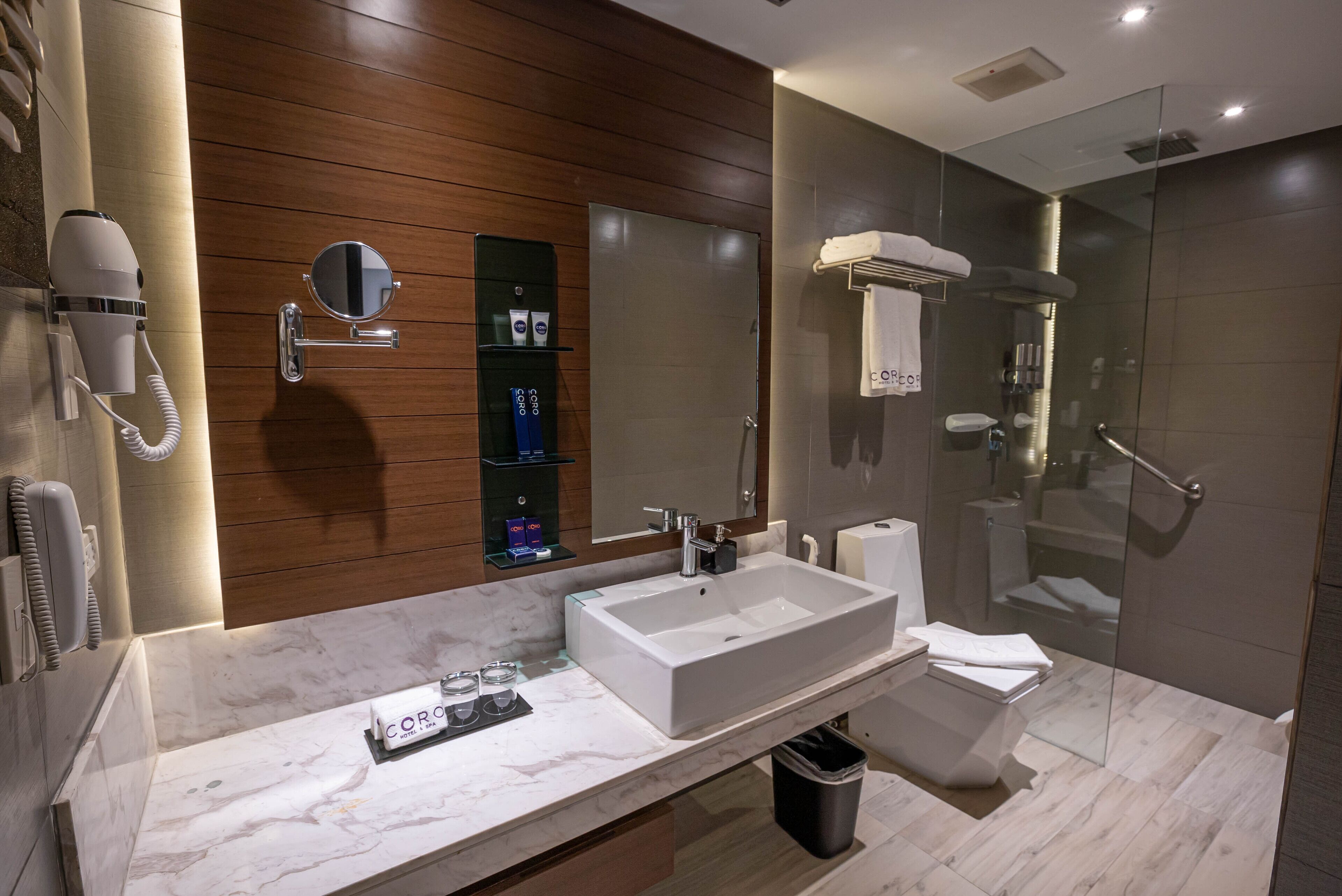 A modern bathroom with a large sink, mirror, and glass shower enclosure.