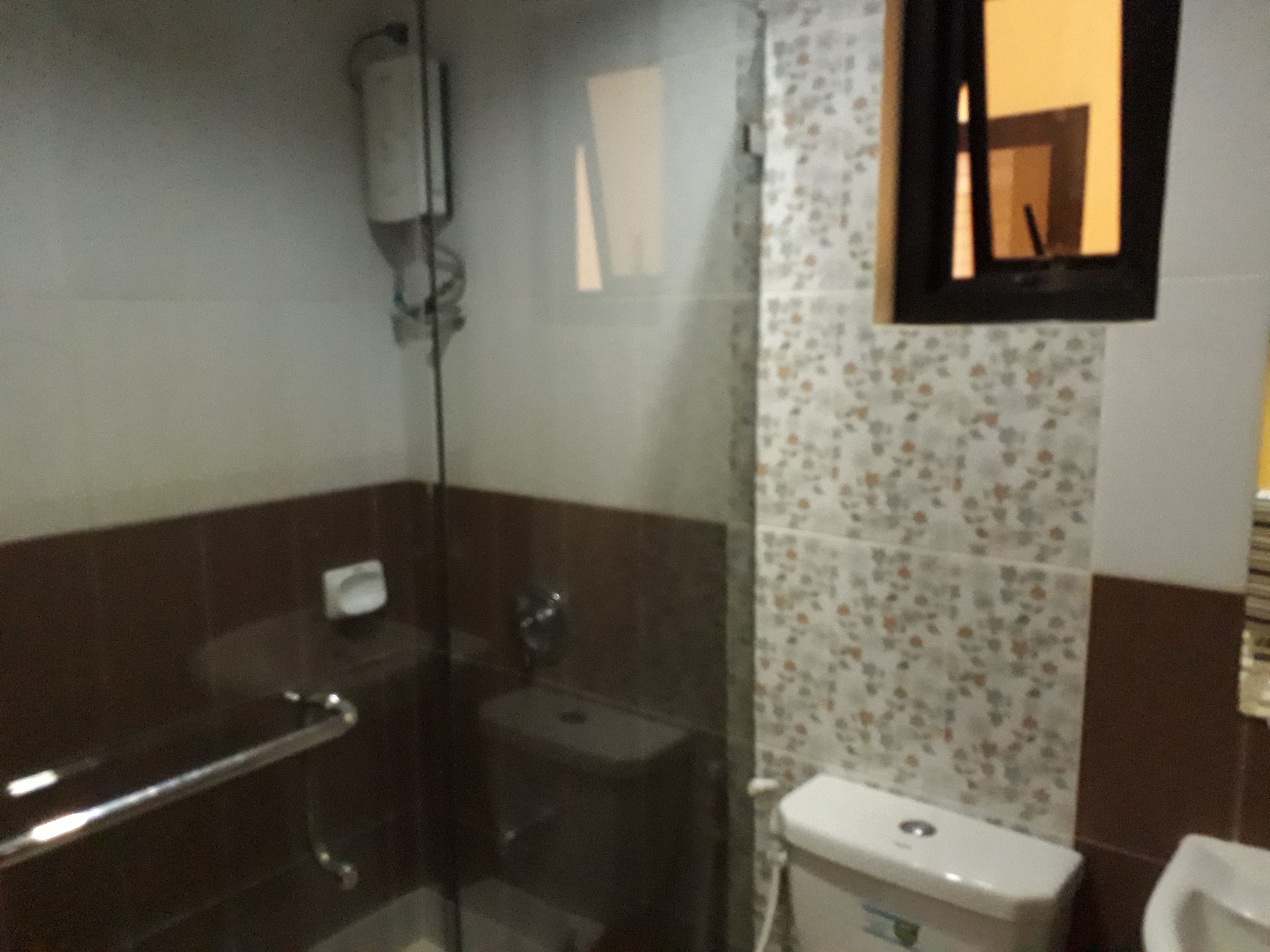 Un baño con cabina de ducha de vidrio, inodoro y lavamanos.