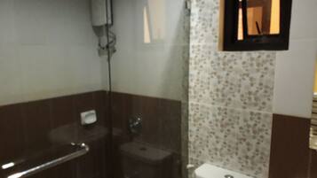 Un baño con cabina de ducha de vidrio, inodoro y lavamanos.
