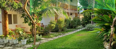 A well-maintained garden with a stone pathway leading to a building with a balcony.