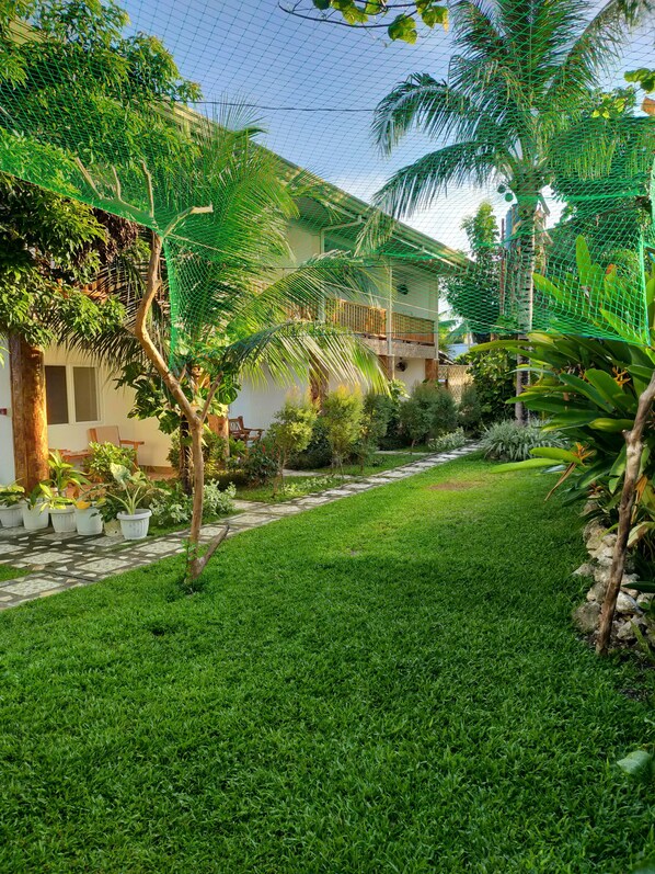 A well-maintained garden with a stone pathway leading to a building with a balcony.