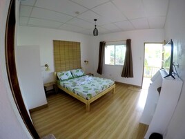A room with a wooden bed, a window with curtains, a ceiling light, and a door.
