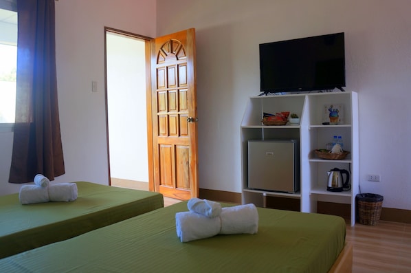 Una habitación de hotel con dos camas, un televisor sobre un mueble y una puerta.