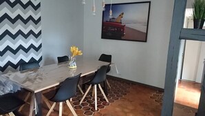 Ein Essbereich mit einem Marmortisch, schwarzen Stühlen, einer Vase mit gelben Blumen und einem Gemälde von einem Auto an der Wand.