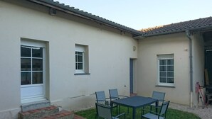 Ein Gebäude mit flachem Dach, einer kleinen Terrasse mit Tisch und Stühlen sowie einer Treppe zum Eingang.