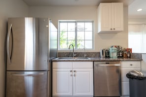 Enjoy cooking in this well-equipped kitchen with stainless steel appliances, a granite countertop, and white cabinetry.