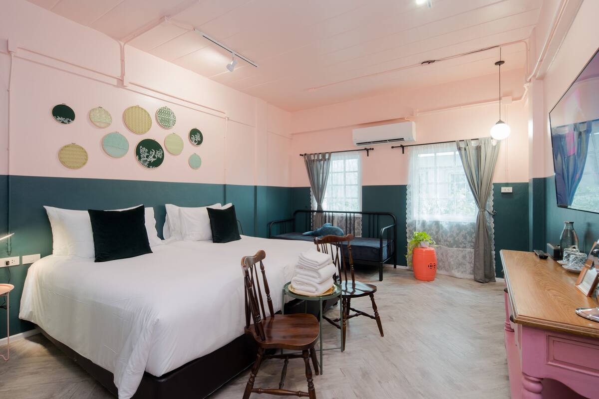 Een goed verlichte hotelkamer met een groot bed, een bureau, een stoel en een kleine tafel met een plant.