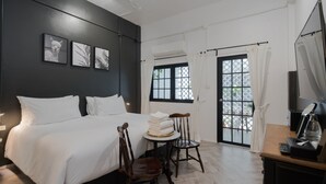 A hotel room with a large bed, two chairs, a small table with towels, a coffee maker, and a view through a window with curtains. - Blu Monkey Boutique Phuket Town (Phuket)