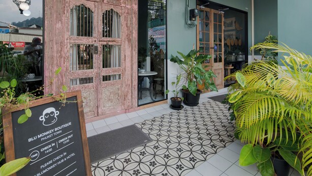 A boutique hotel entrance with a vintage wooden door, a check-in board, and potted plants. - Blu Monkey Boutique Phuket Town (Phuket)