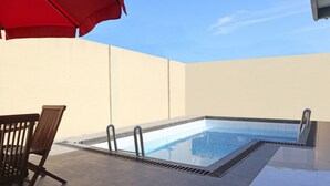 A rooftop pool area with a chair and umbrella, surrounded by walls. - OYO 1326 Mahakam Guest House (Padang)