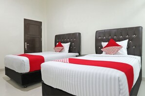 Two beds with black headboards and white bedding are positioned in this hotel room.