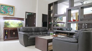 A living room with a dark leather sofa, a coffee table, and a fish tank. - OYO 1326 Mahakam Guest House (Padang)