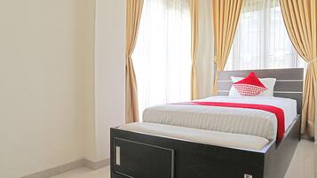 A modern bedroom with a large bed, a nightstand, and a window with curtains.