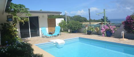 Ein Swimmingpool mit klarem, blauem Wasser, umgeben von Kübelpflanzen und einer Holzterrasse.