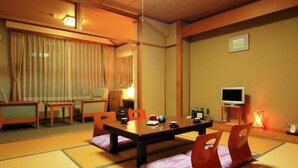 A traditional Japanese-style room with tatami flooring, a low table with cushions, and a television on a stand. - Yasuragiso (Joetsu)