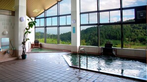 A large indoor swimming pool with a view of a forested hillside through large windows. - Yasuragiso (Joetsu)