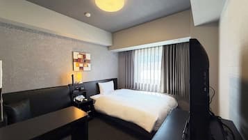 Una habitación de hotel con cama, escritorio, televisor, lámpara y una obra de arte en la pared.