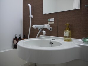 A bathroom with a white sink, a handheld showerhead, a bottle of liquid soap, and a small mirror. - Hotel Route-Inn Grand Ota Ekimae (Ota)