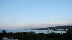 A coastal landscape with a clear sky, a body of water, and distant hills. - Casa Botanika (Yomitan)