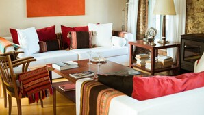 A living room with a white sofa, red and white pillows, a wooden coffee table, and a bookshelf with books. - Estancia Anastasio by Folk (Maldonado)