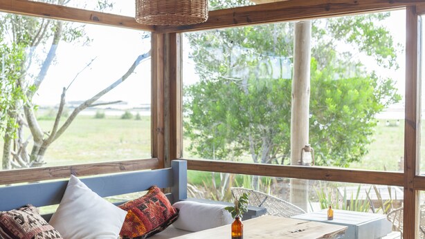 A wooden bench with cushions and a small table with a vase. - Estancia Anastasio by Folk (Maldonado)