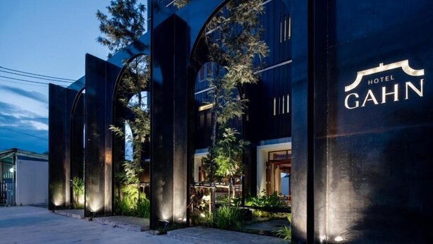 A modern hotel with a dark facade, large arched windows, and a visible entrance.