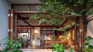 A traditional Japanese-style interior with wooden beams, tatami flooring, and a central seating area.