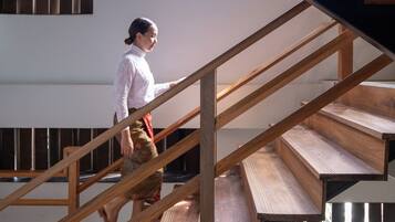 Eine Person geht eine Holztreppe hinunter, deren modernes Design sichtbare Balken und eine minimalistische Ästhetik aufweist.
