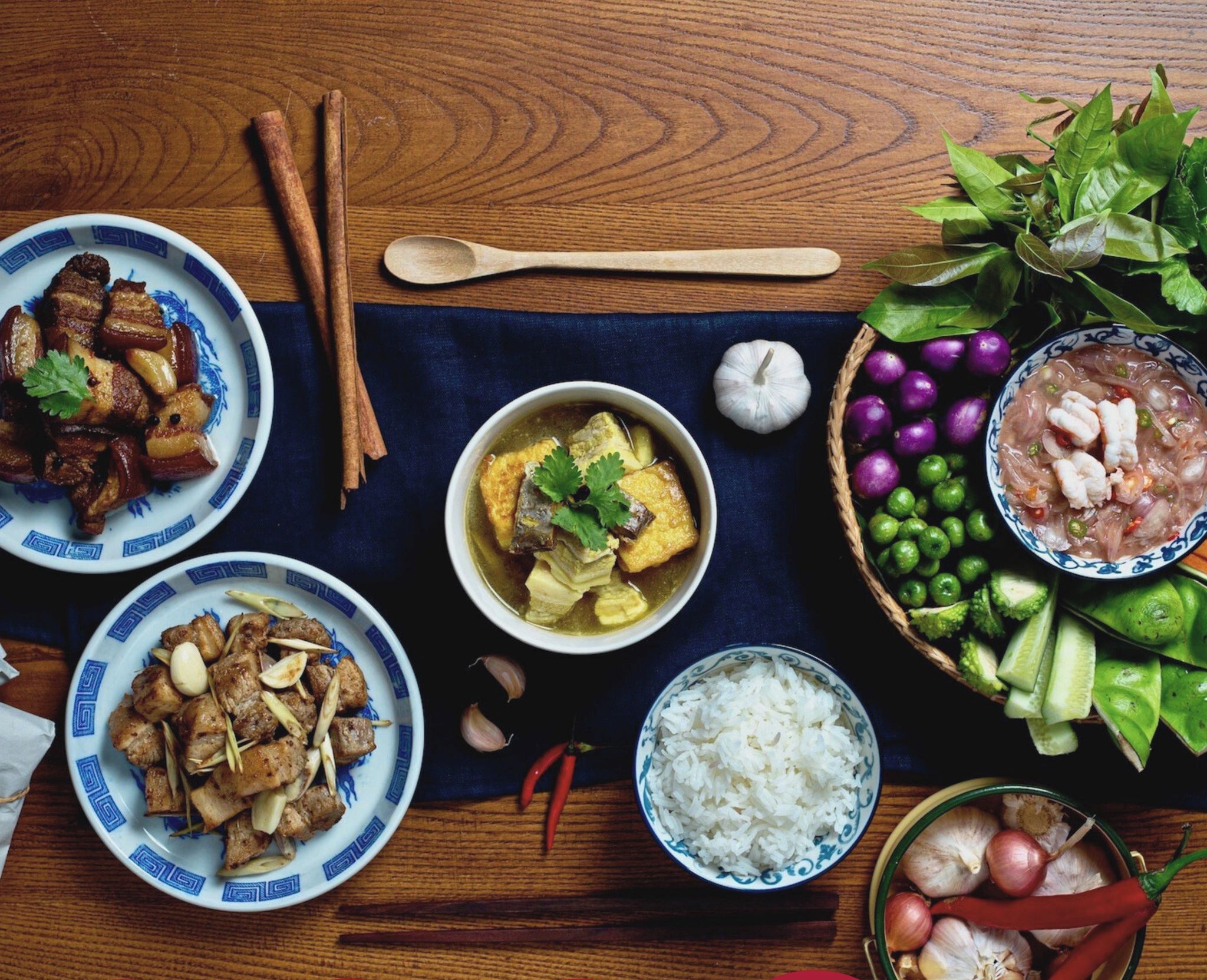 Une table dressée avec différents plats, notamment de la viande, des légumes et du riz, ce qui laisse supposer qu’il s’agit d’un repas.