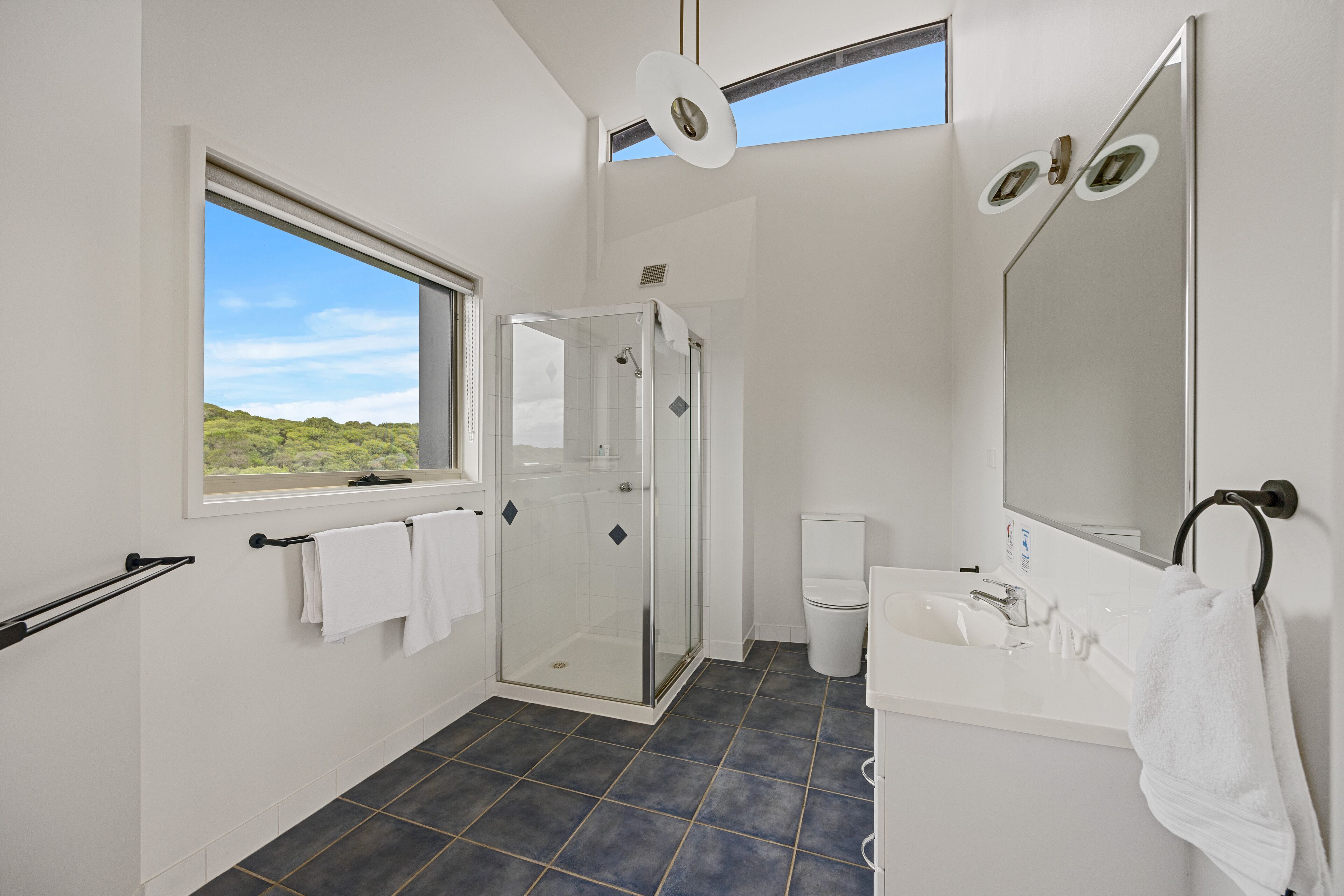 A modern bathroom with a glass-enclosed shower, a white sink, and a large mirror.