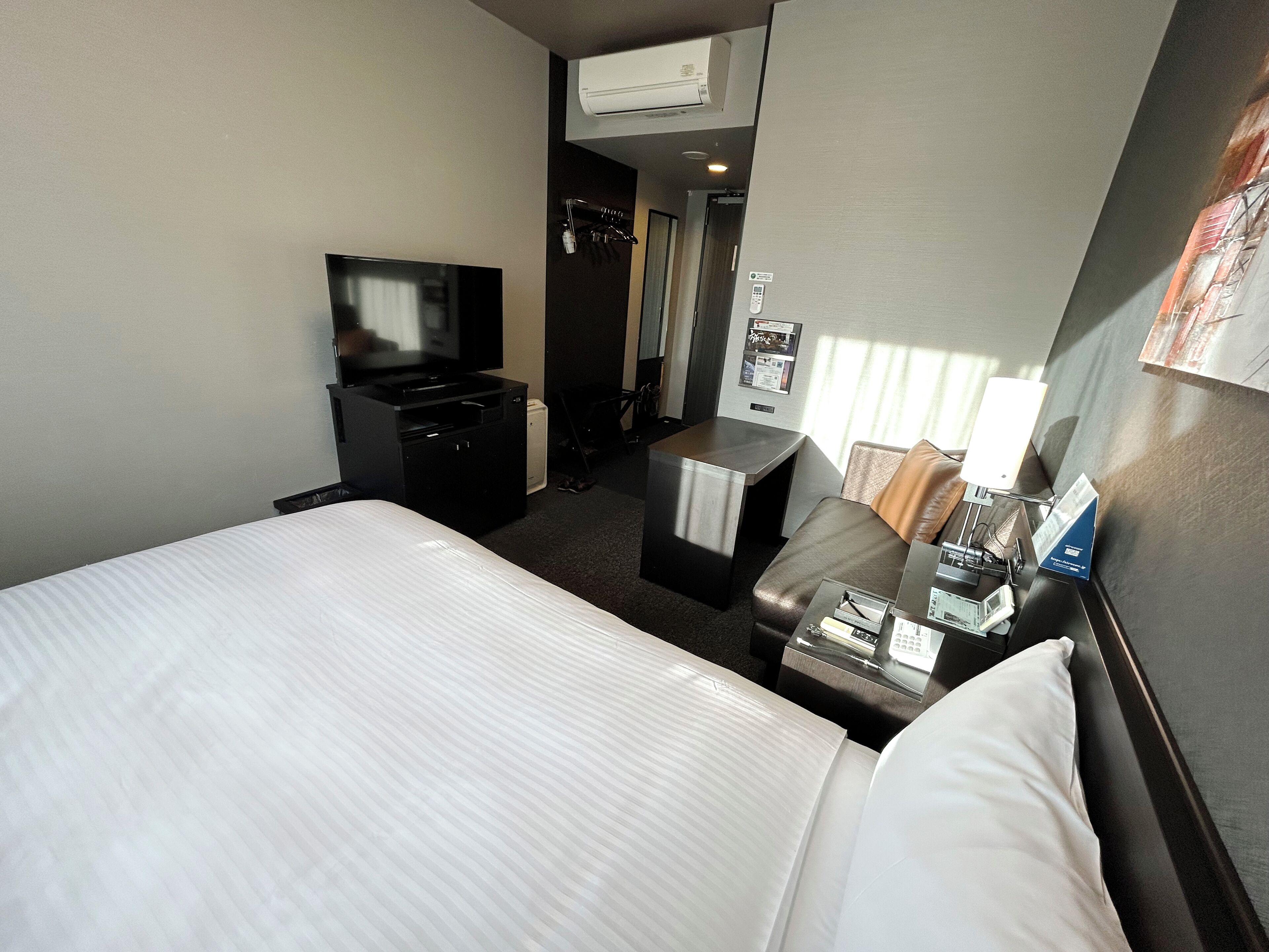 Habitació d'hotel amb llit, escriptori, televisió i minibar.