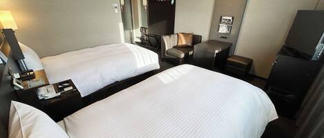 Une chambre d’hôtel avec deux lits, un bureau, une chaise, une télévision et un mini-bar.