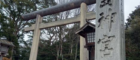 A stone monument with carved text, a traditional wooden structure, and a stone wall.