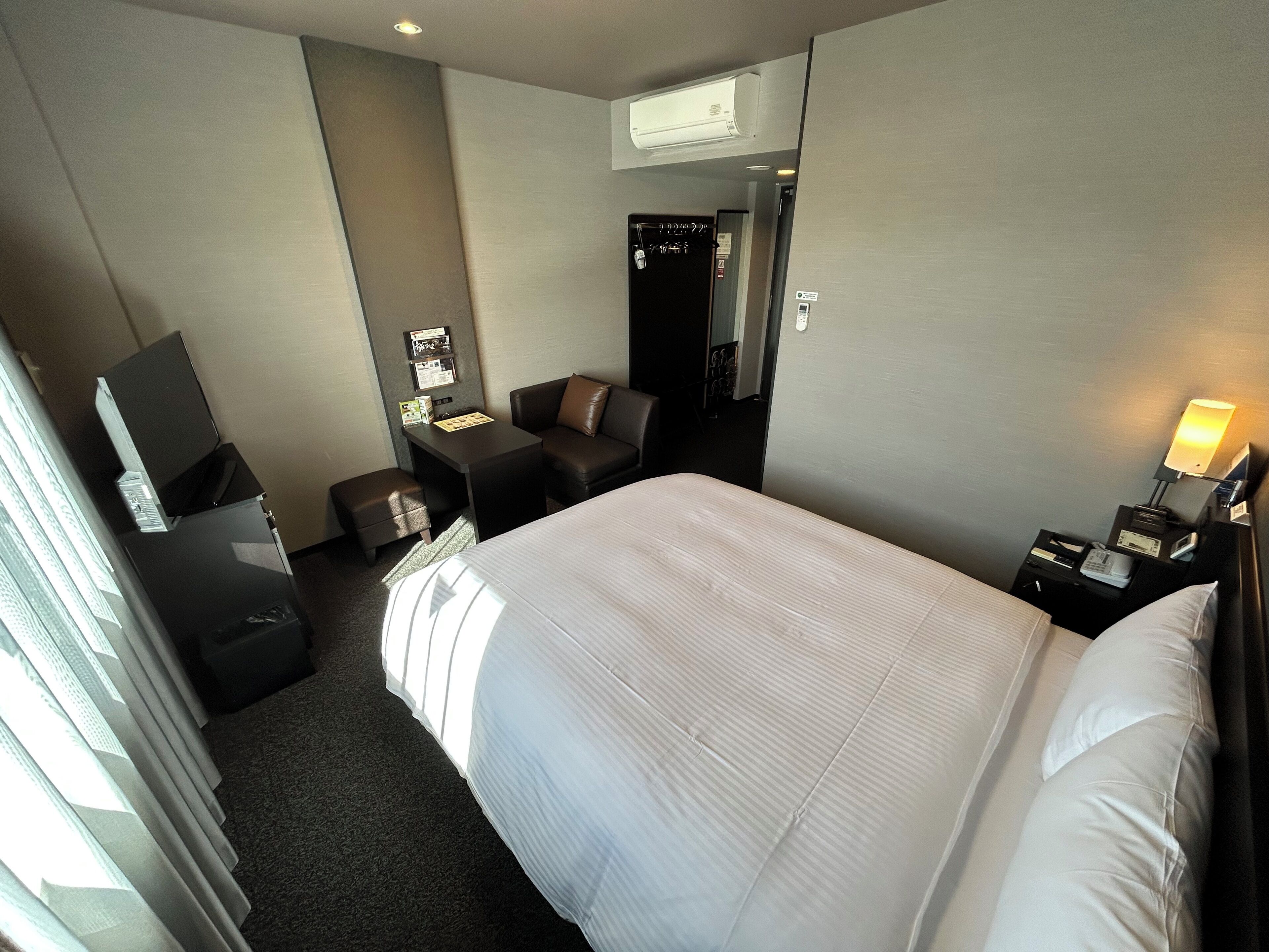 Une chambre d’hôtel avec un grand lit, un bureau, une chaise, une télévision et une lampe de bureau.