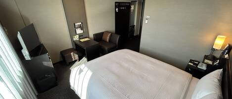 Une chambre d’hôtel avec un grand lit, un bureau, une chaise, une télévision et une lampe de bureau.