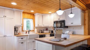 A modern kitchen with white cabinetry, a central island, a microwave, and a coffee maker.