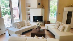 Una sala moderna con chimenea, sofás blancos y una mesa de centro.