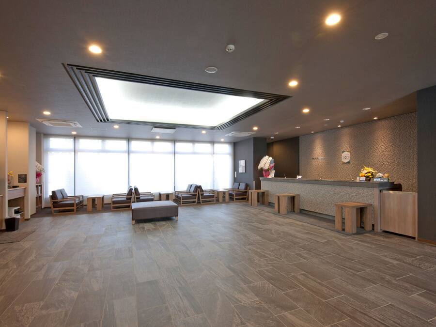 A spacious lobby with a reception desk, seating area, and large windows allowing natural light.
