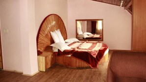A bedroom with a wooden headboard, a bed with white bedding, a mirror, and a wooden bench. - Zarim Hotel Manali (Manali)