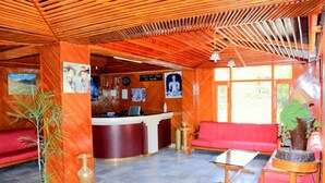 A reception area with a wooden ceiling, red seating, a reception desk, and various wall decorations. - Zarim Hotel Manali (Manali)
