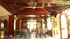 A spacious dining area with high ceilings and wooden beams, featuring tables and chairs arranged for dining. - Zarim Hotel Manali (Manali)