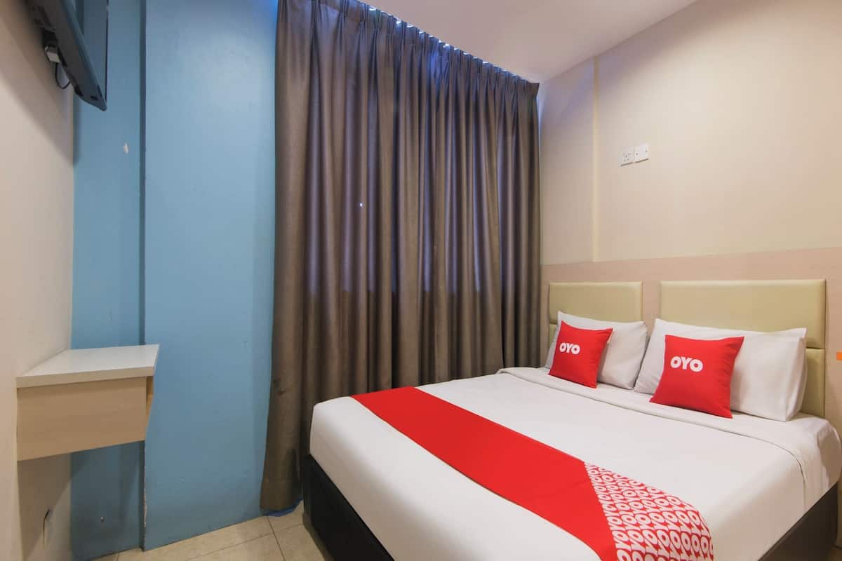 Une chambre d’hôtel avec un lit, une table de chevet, une fenêtre avec des rideaux et un mur muni d’un interrupteur.