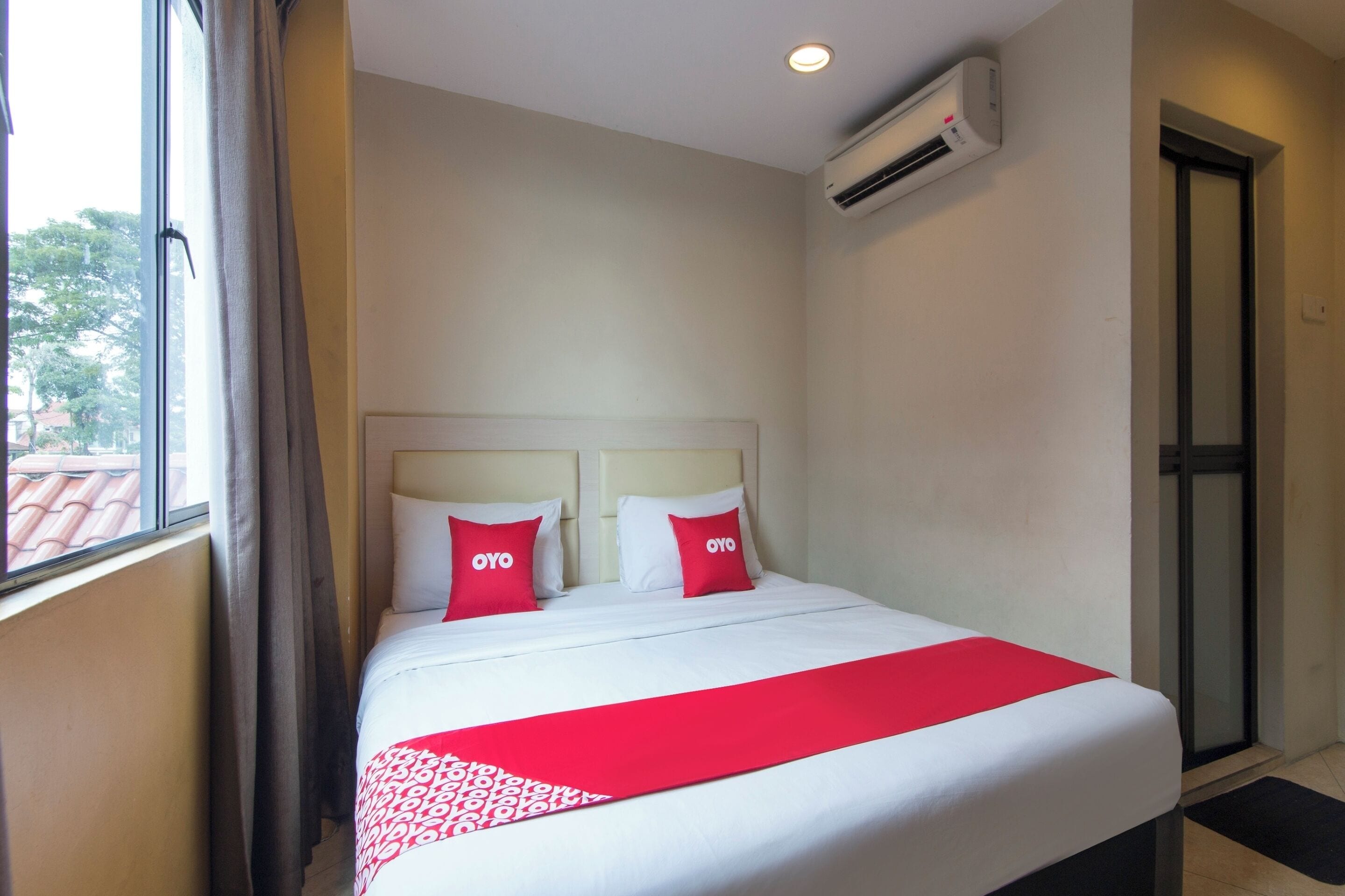 Una habitación de hotel con cama, aire acondicionado y ventana con cortinas.
