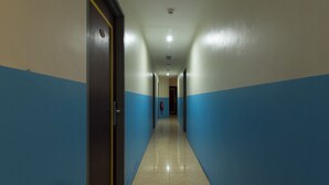 Un long couloir étroit aux murs bleus et beiges, doté d’un sol carrelé et d’une porte située sur le côté gauche.