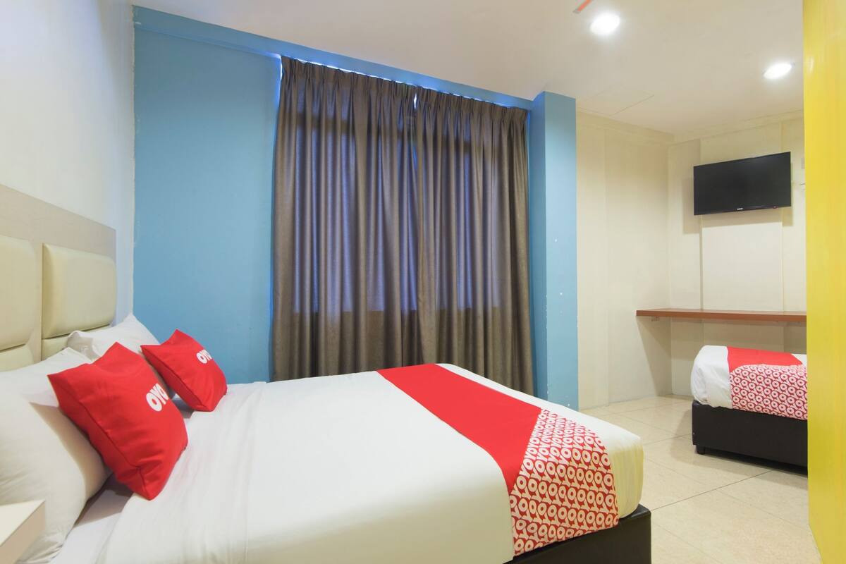 Une chambre d’hôtel avec un lit, une télévision et une fenêtre avec des rideaux.