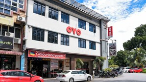Un hôtel affichant une enseigne « OYO » bien visible, un magasin de peinture « Colourland paints » et une autre enseigne « Hotel OYO » indiquant qu’il compte 910 chambres.