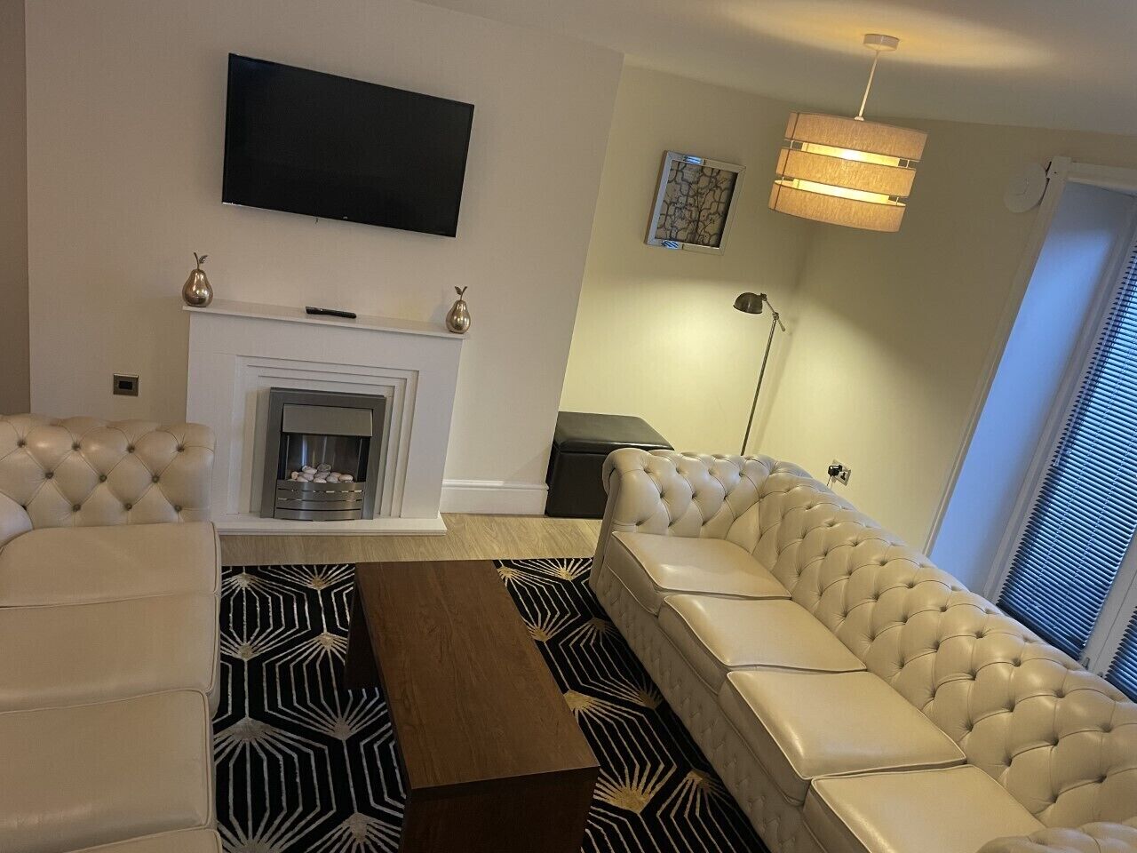 A living room with a fireplace, a sofa, a coffee table, and a TV mounted on the wall.