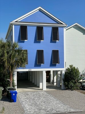 A two-story building with a blue exterior and white trim, featuring a covered entrance and a visible address number.